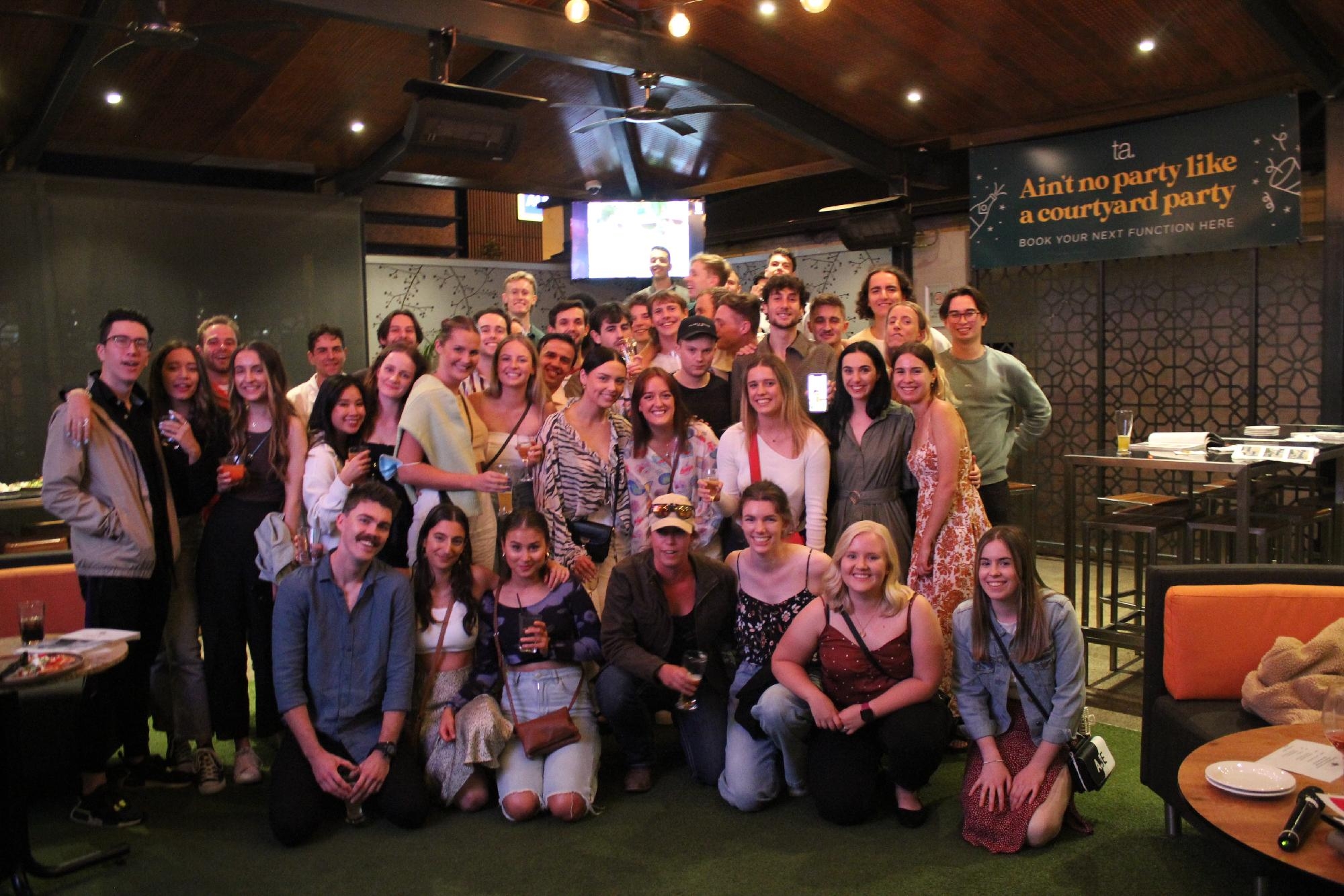 Large group of Mercedes College alumni gathered indoors for a MOSA reunion celebration.
